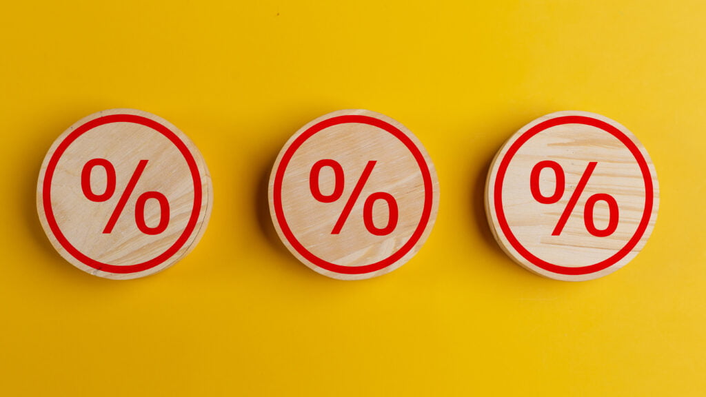 Percent sign on wooden cubes against yellow background with copy space. Concept of sale
