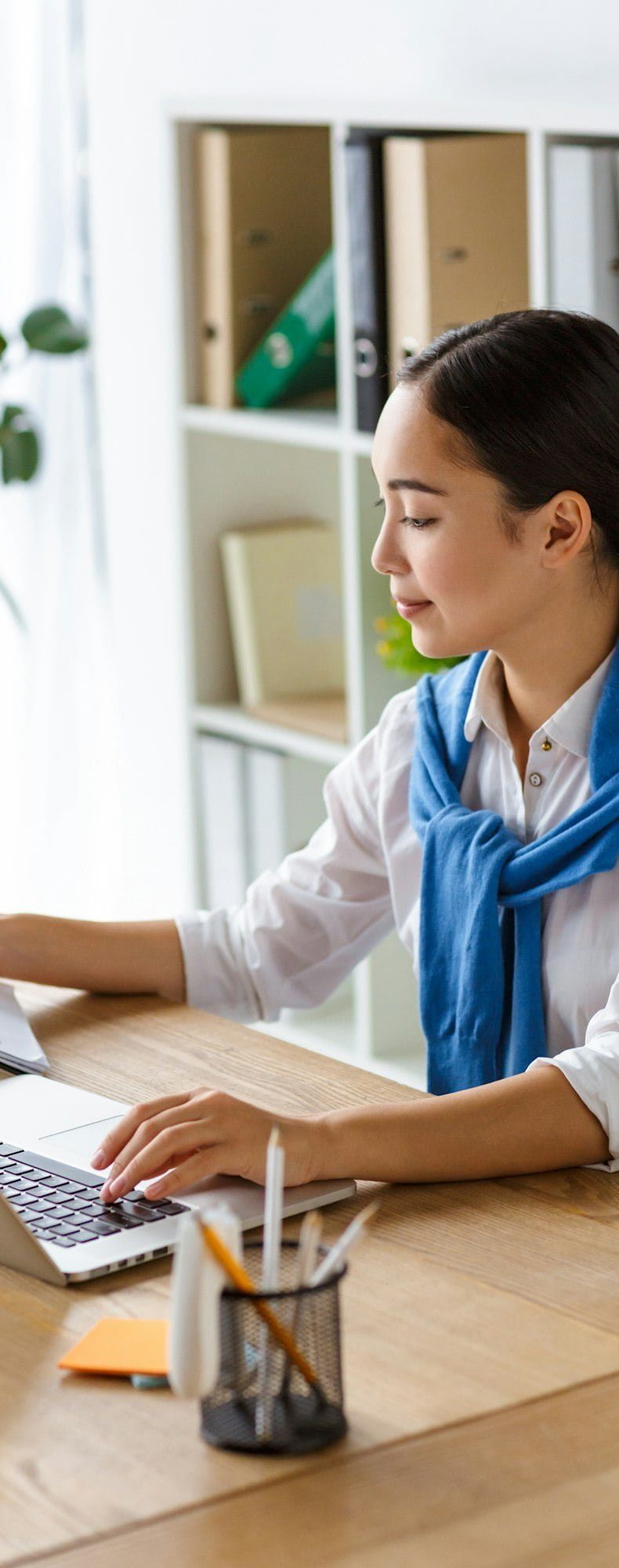 Image of young asian woman using laptop computer while working in office