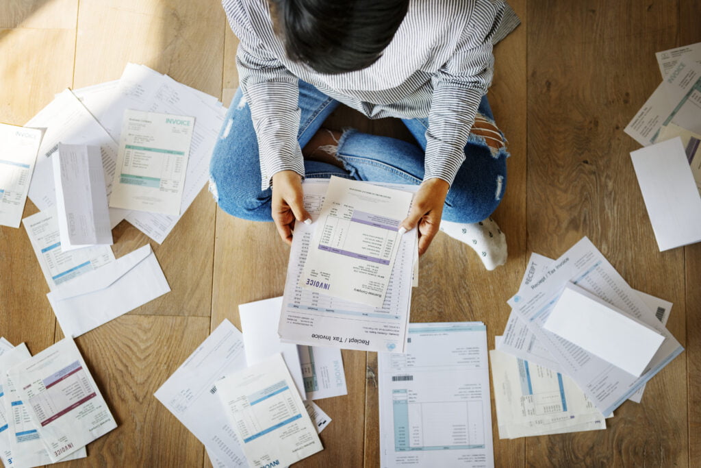 Sorting out a pile of bills on the floor