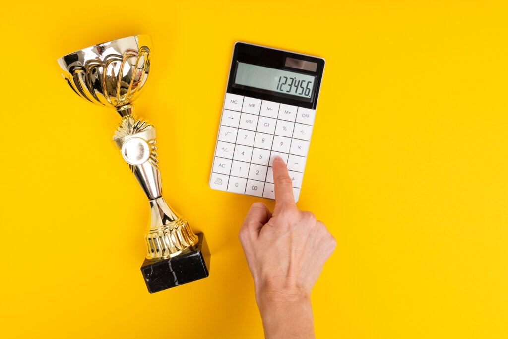 calculator and winner cup lie on a yellow table with copy space