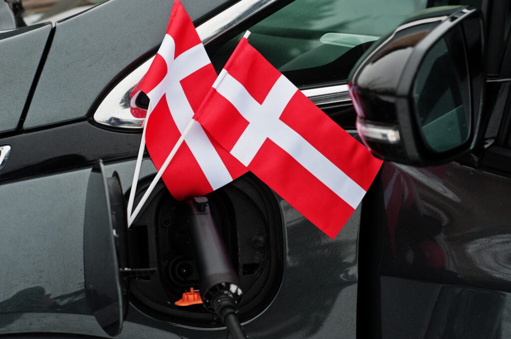 Denmark flag ecological car concept. Plugging a power supplier, charging modern automobile.