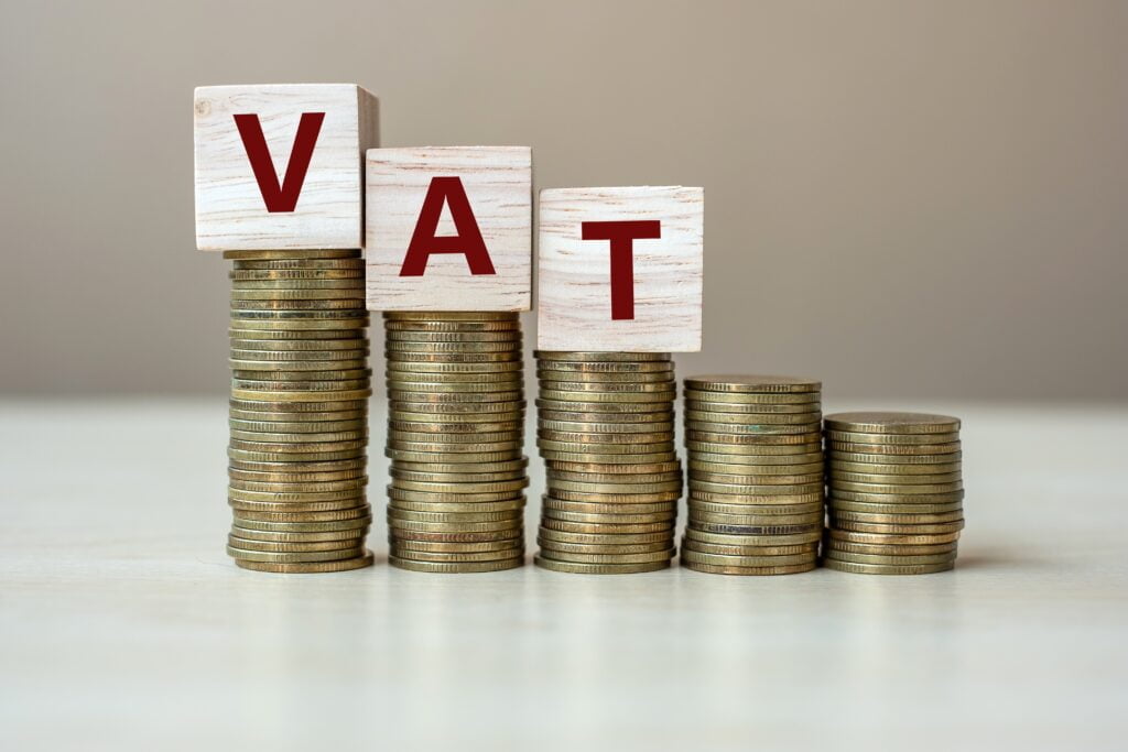 VAT wooden cube with golden coin on growing money stairs
