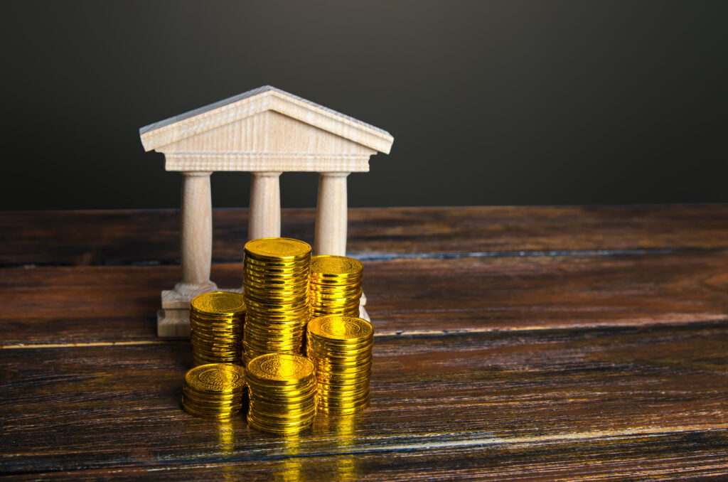 Bank building and coins stacks. State debt. Budget. Tax collection.