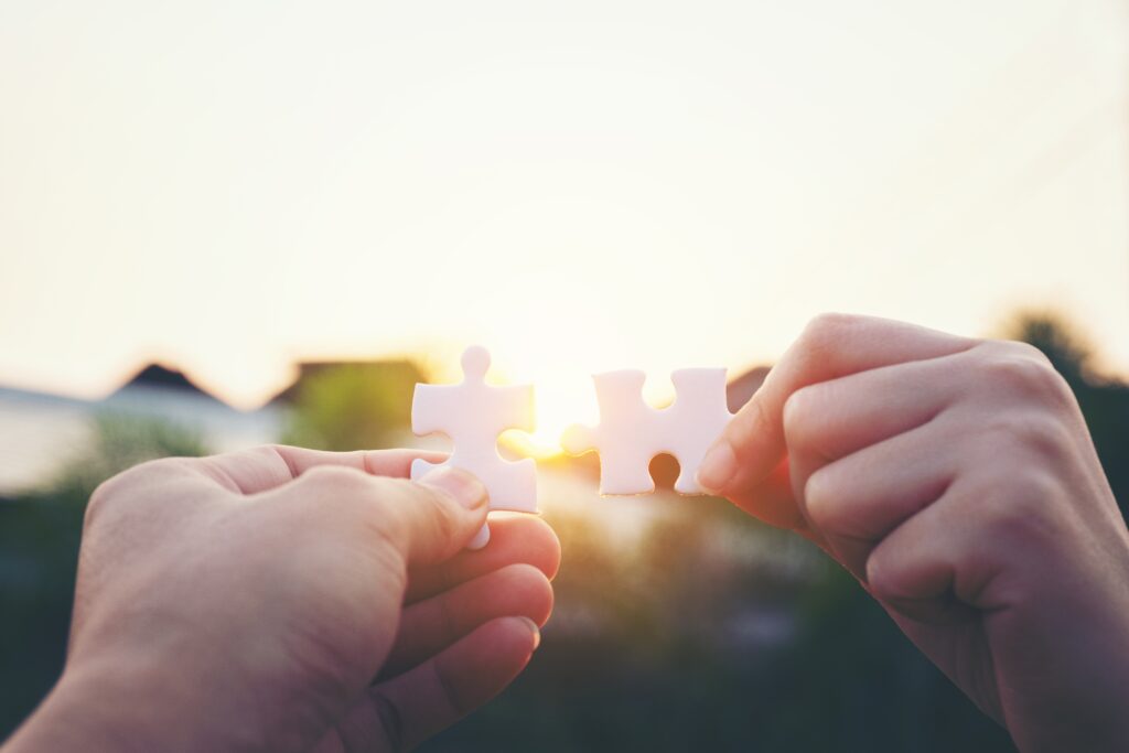 Closeup hand of woman connecting jigsaw puzzle with sunlight, symbol of association and connection
