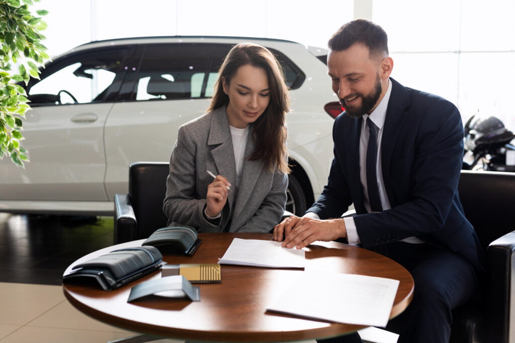 a young woman buys her first car in a car dealership and signs a contract to buy insurance