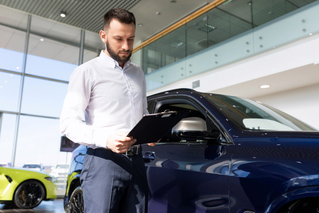 the seller at the car dealership prepares documents for the buyer of the car