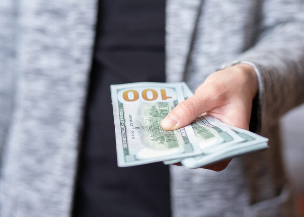 The woman gives money. female hands hold and serve cash banknotes of 100 dollars